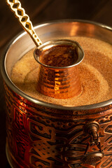 Traditional Turkish coffee with foam in cezve prepared on hot sand in authentic Turkish Copper.