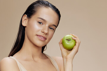 young woman with a green apple smile beige background