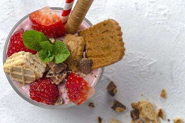Homemade Yogurt with red berries, cookies and chocolate on white wooden table