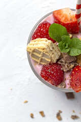 Homemade Yogurt with red berries, cookies and chocolate on white wooden table