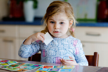 Excited smiling cute toddler girl playing picture card game. Happy healthy child training memory,...