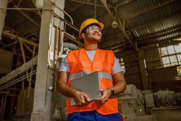 Multiethnic engineer working with laptop at plant