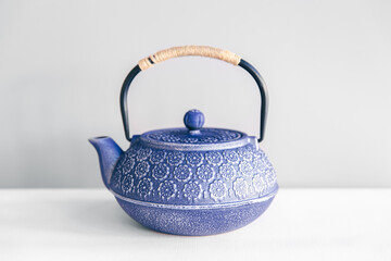 Blue cast iron teapot on a white background.