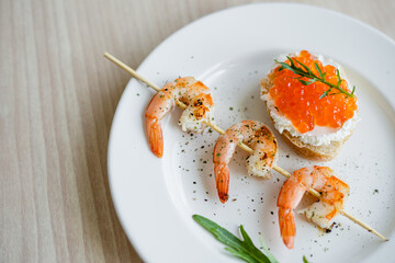 delicious grilled shrimps on a skewer, toast with curd cheese, red caviar and arugula