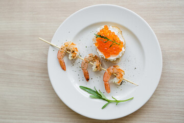 delicious grilled shrimps on a skewer, toast with curd cheese, red caviar and arugula