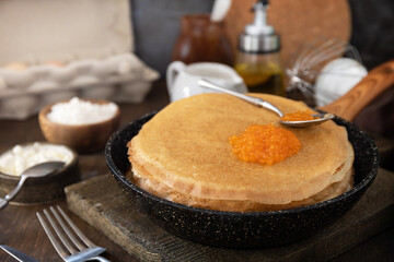 Pancakes traditional Russian cuisine. Thin lacy pancakes served with red caviar on a wooden table.