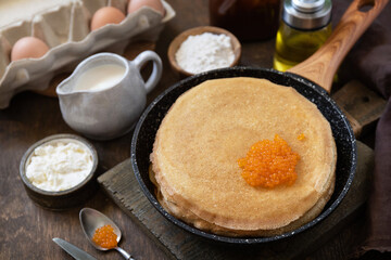 Pancakes traditional Russian cuisine. Thin lacy pancakes served with red caviar on a wooden table.