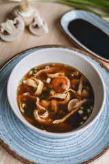 Homemade asian spicy soup style with soy sauce and mushrooms champignons and big prawn