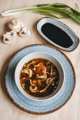 Homemade asian spicy soup style with soy sauce and mushrooms champignons and big prawn