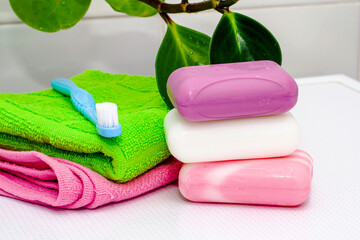 a stack of towels soap toothbrush and houseplant on the bathroom table