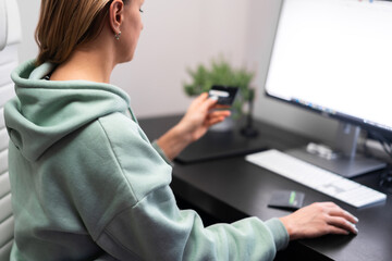 young woman sitting at the computer and purchasing online with credit card at home. Internet bank, online shopping, technology and e-money concept