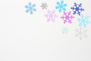Colored snowflake paper crafts on white textured paper background for wall paper.  Blank for copy space.