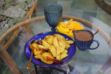 Sliced lemons, tkemali in a blue gravy bowl and glasses on a glass table