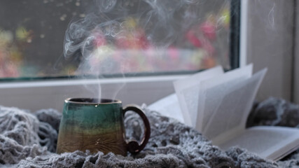Steaming coffee cup on a rainy day window background. cozy atmosphere, in cold weather. Rainy Day Mood. warming home atmosphere