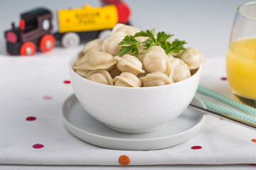 Homemade Meat Dumplings or tortellini in child hands. Traditional Russian food- pelmeni