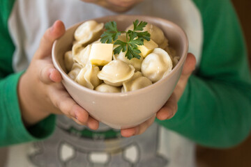 Homemade Meat Dumplings or tortellini in child hands. Traditional Russian food- pelmeni