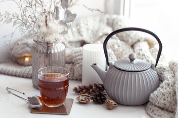 Cozy Scandinavian composition with teapot, a glass of tea, and decor details.