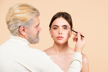 Professional man visagiste make up artist combing brows. Combs eyebrows with a brush in a beauty...