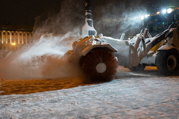 Winter service vehicle clearing thoroughfares of ice and snow, yellow snow plow tractor working on...