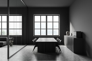 Dark meeting interior with seats, table and commode near panoramic window