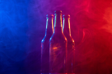 Three bottles of beer in a blue-pink mist.