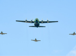 Large military cargo plane flying over Bucharest, escorted by three fighter planes.