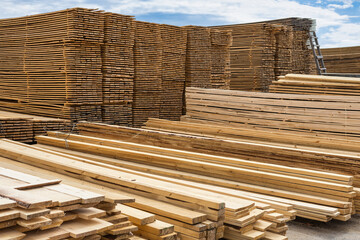 Industrial warehouse of finished lumber products in the open air, wood stacked in piles on a large...