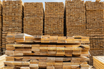 Wooden boards, slats, lumber in the foreground. Stacked lumber. Folded wood. Boards in the warehouse.