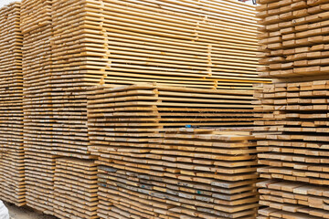 A lot of boards stacked on top of each other in the warehouse. Lumber for further use in construction.