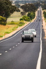 Cars travelling along a very long, straight single lane paved highway in rural New South Wales,...