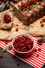 Cranberry sauce with Traditional French terrine on dark wooden background with Christmas decorations
