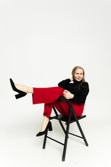 Fototapeta premium Business lady on white background.full length photo of attractive chic businesswoman sitting in bossy comfortable chair, flirtatious mood, looking away towards empty space, wearing red pants