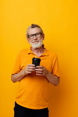 elderly man in a yellow T-shirt a glass with a drink yellow background