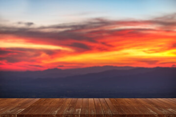 Wooden table and blur of beauty, sunset sky, and mountains as background.