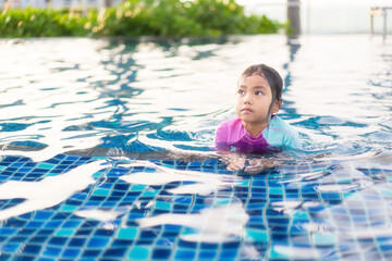 Asian child cute or kid girl wearing keep temperature swimsuit on swimming pool and smile with summer happy in water park for learn and enjoy swim or refreshing relax to exercise at school or hotel