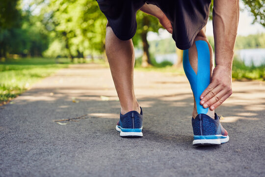 Runner holding injured achilles tendon with kinesiology tape