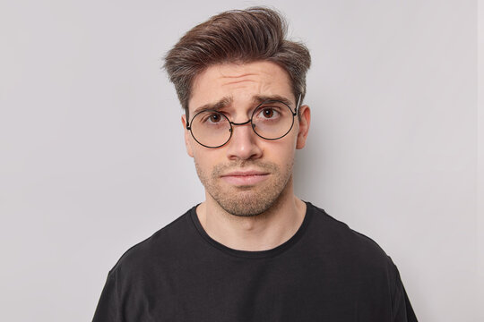 Upset young man with bristle feels disappointed and envy regrets missing chance stands unhappy frowns face dressed casually isolated over white background. Negative emotions and feelings concept
