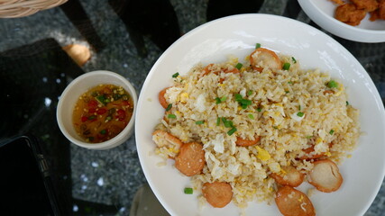 The top view of a dish of sausage fried rice on the grass table