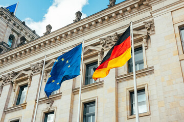 looking up at the flags of the european union and Germany waving in the wind in front of the...