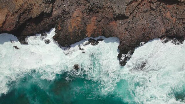 top view. Waves crash on the rocky shore.
