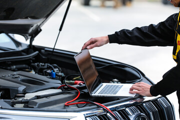Mechanic using computer for diagnostics engine. Repairing car. Blur garage auto repair service in background.