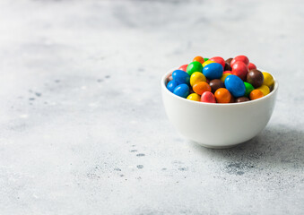 Milk chocolate sweet candies with a rice centre in a sugar shell in white bowl on light background