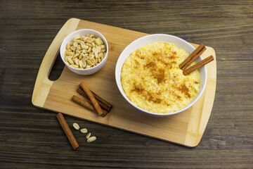 Corn porridge with cinnamon and peanuts on a wooden stand