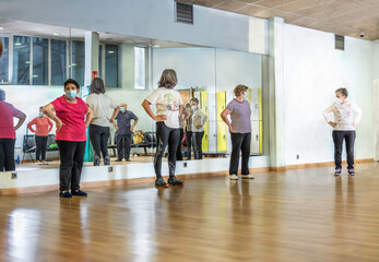 Fototapeta premium Group of retired seniors attending gym class. Wearing protective mask, social distancing. Concept of active retirement.
