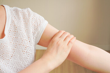 woman's hand in white t-shirt touch her upper arm , arm pain and muscle injury concept