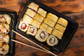 Fototapeta na wymiar sushi in a black plastic container on a wooden background