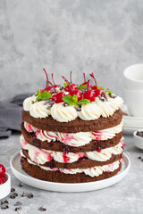 Naked Black forest cake, Schwarzwald pie. Cake with dark chocolate, whipped cream and cherry on a gray concrete background. Copy space.