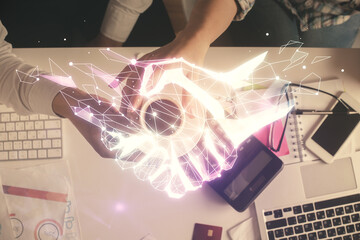 Double exposure of man and woman working together and the handshake hologram drawing. Computer background. Top View.