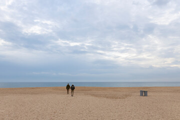 Sea coast on an autumn cloudy day. Two men and two trash cans on the beach. Original composition with a sea landscape.