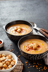 Lentil cream soup with paprika and crouton in black ceramic bowls